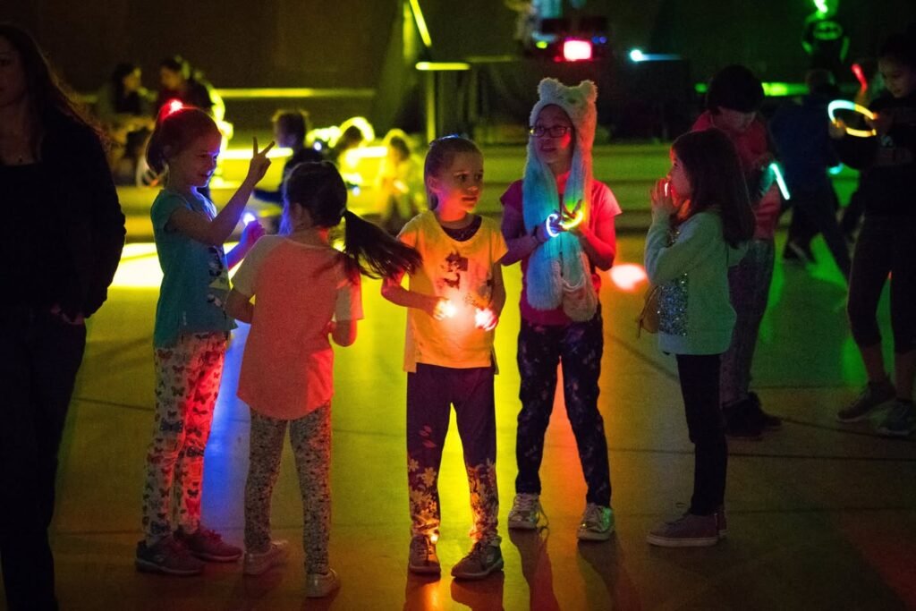 Children enjoying a nighttime glow event, wearing glowing outfits.