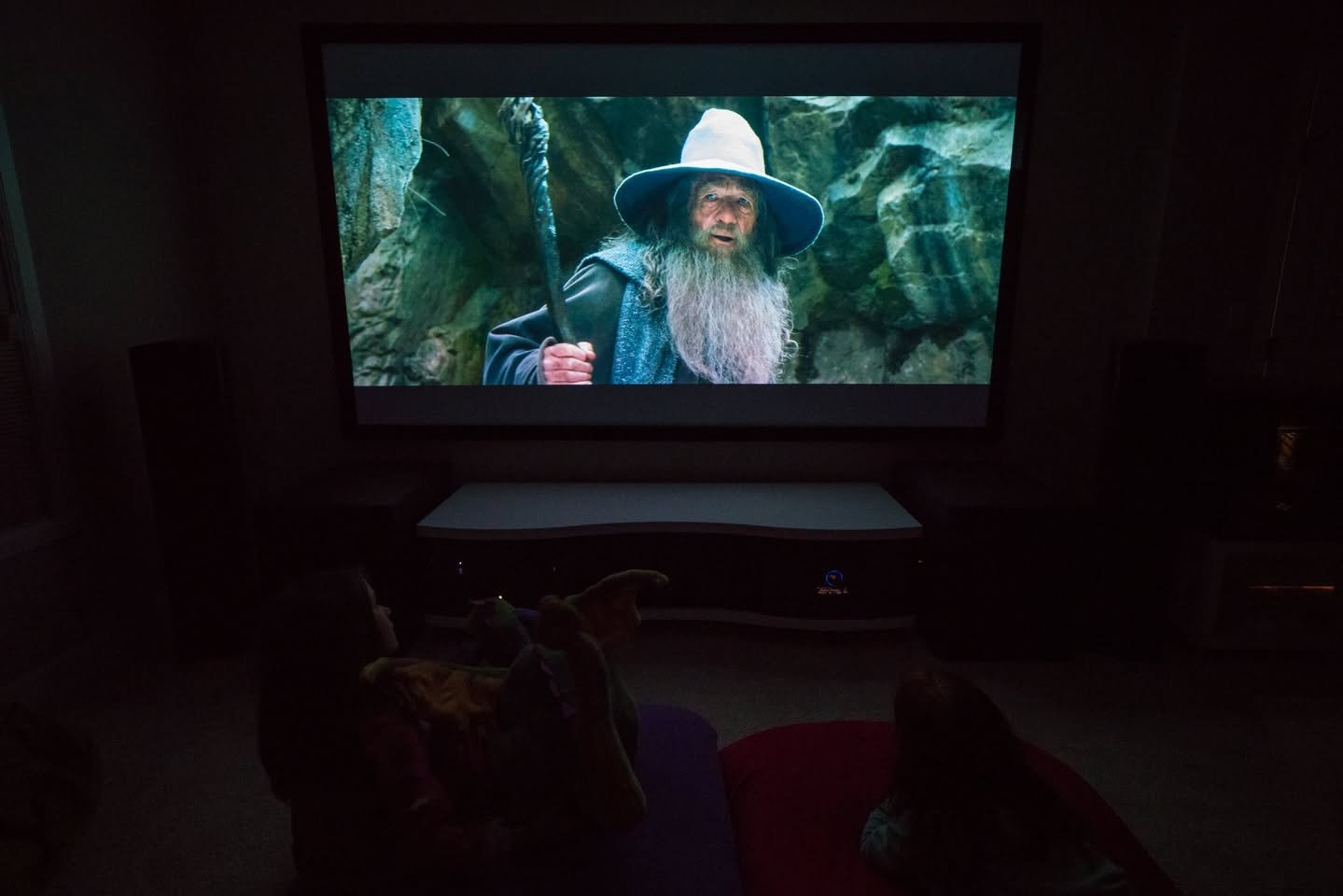 North Creek, Washington A dark home theater with a projector displaying a scene from a fantasy film featuring a wizard in a wide-brimmed hat.