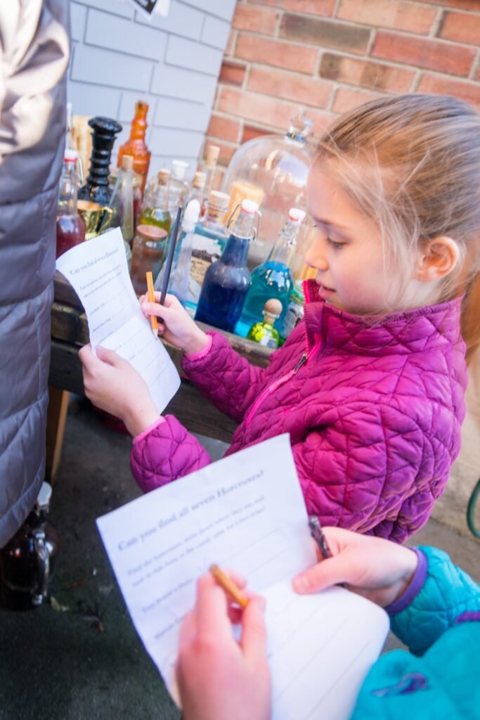 A young student in a bright pink jacket takes notes during a science activity outdoors in the Pacific Northwest.