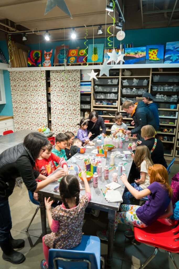 Children engaging in a craft project at a long table under colorful decorations.