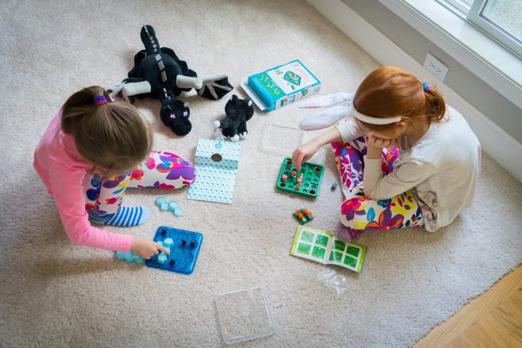 Two children assembling a STEM toy kit with colorful panels on a living room carpet near a window.