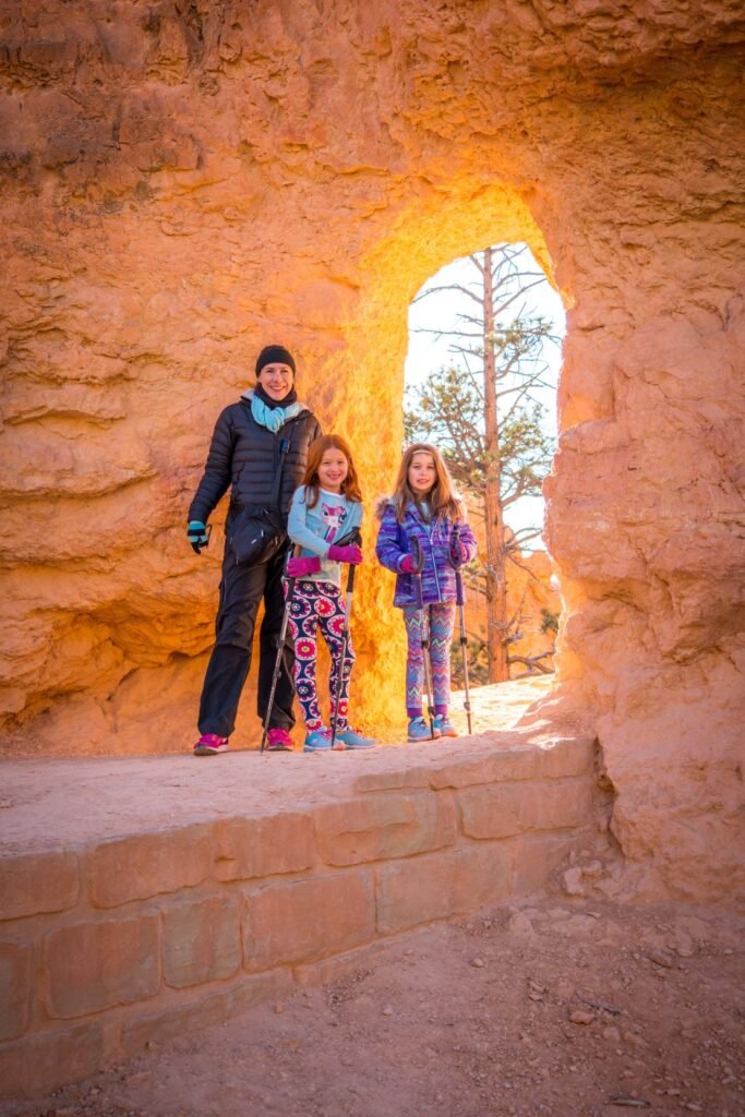 A family of three poses inside a natural sandstone arch during a winter day with snow.