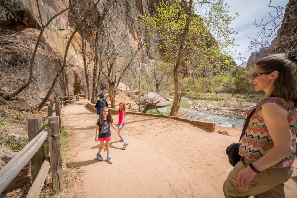A group of hikers exploring a sandy trail in a canyon with dramatic rock formations.