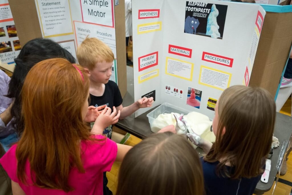 Children observe colorful science fair project boards at an indoor exhibition with informational posters.