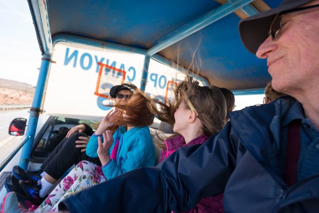 Travelers enjoying an open-jeep tour with wind blowing through their hair during a scenic adventure.