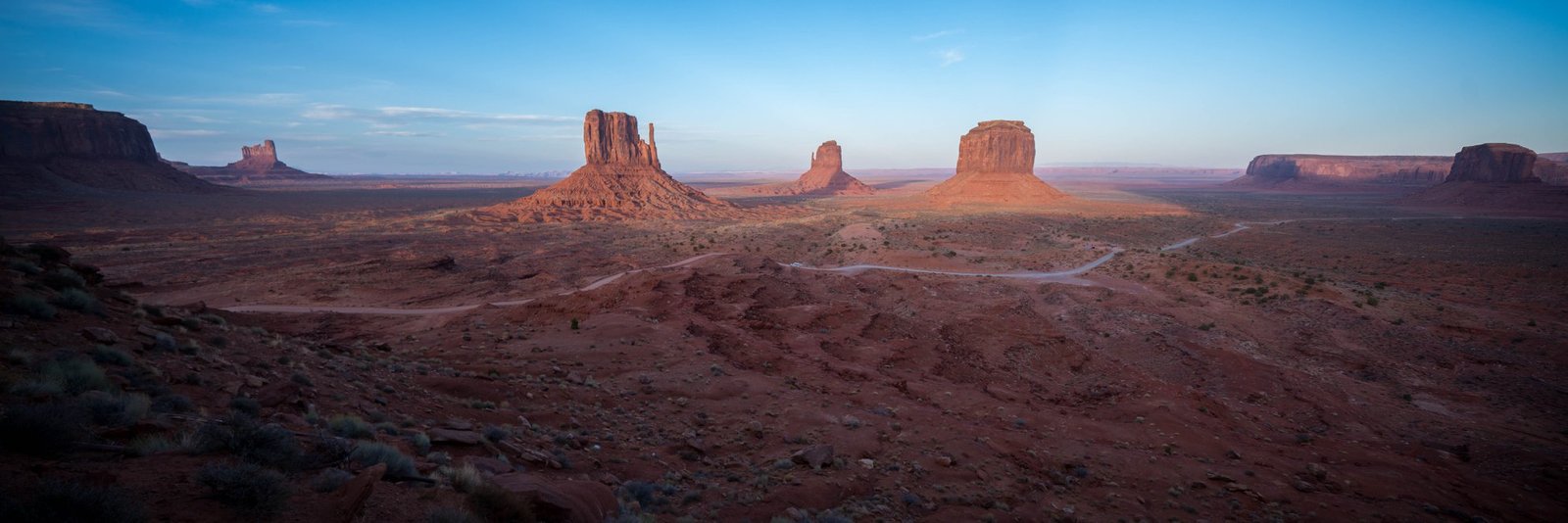Monument Valley A wide-angle view of desert mesas and buttes at twilight, facing a distant plateau.