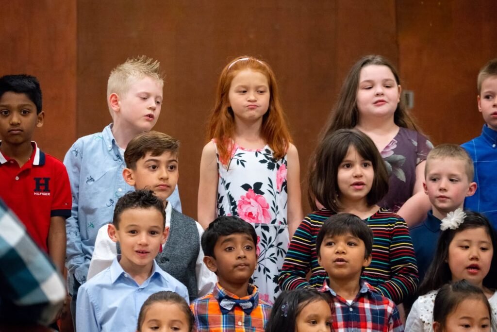 Diverse group of children performing in a choir formation with warm lighting.