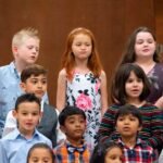 Monument Valley Diverse group of children performing in a choir formation with warm lighting.