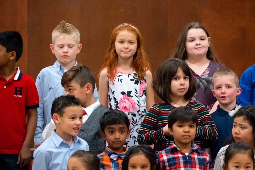A group of young students gathered together at what appears to be a school event, dressed in various casual outfits.