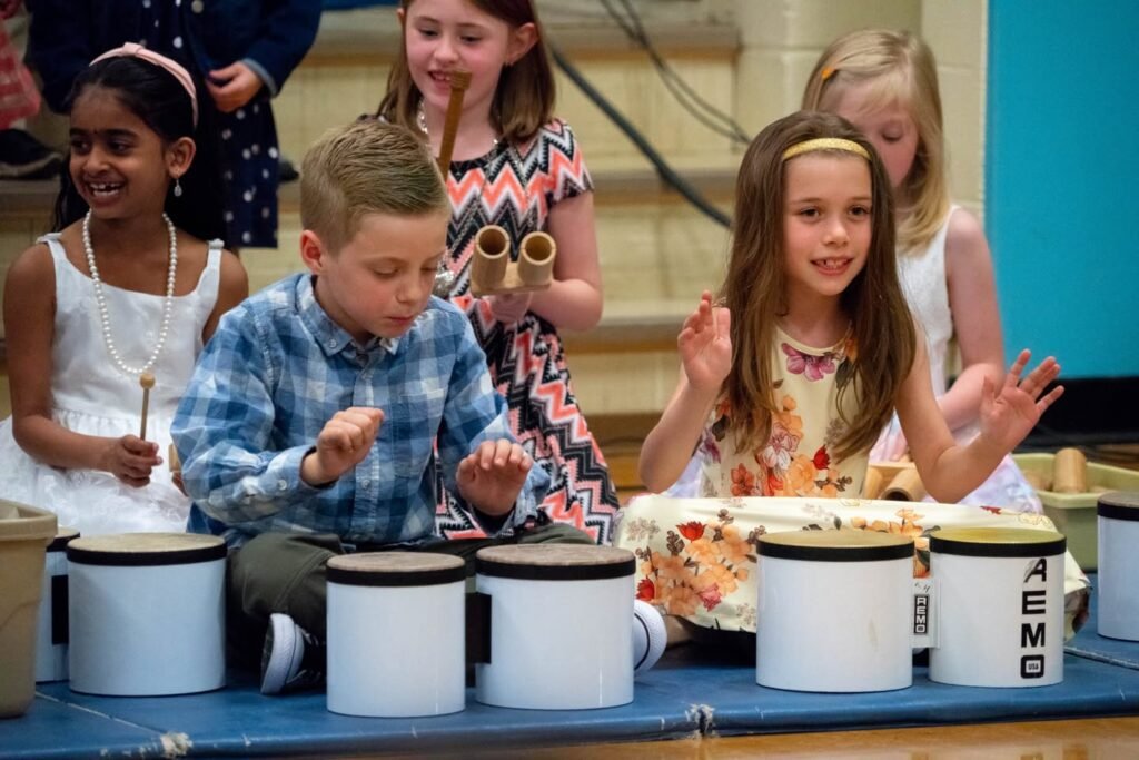 Children participating in a music workshop with djembe drums and percussion instruments.