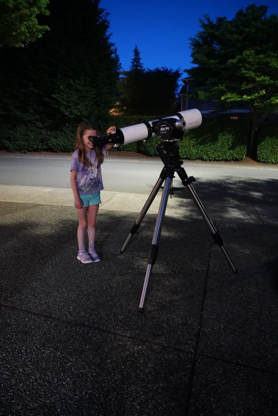 Jupiter A child peers through a telescope set up on a tripod during twilight hours.
