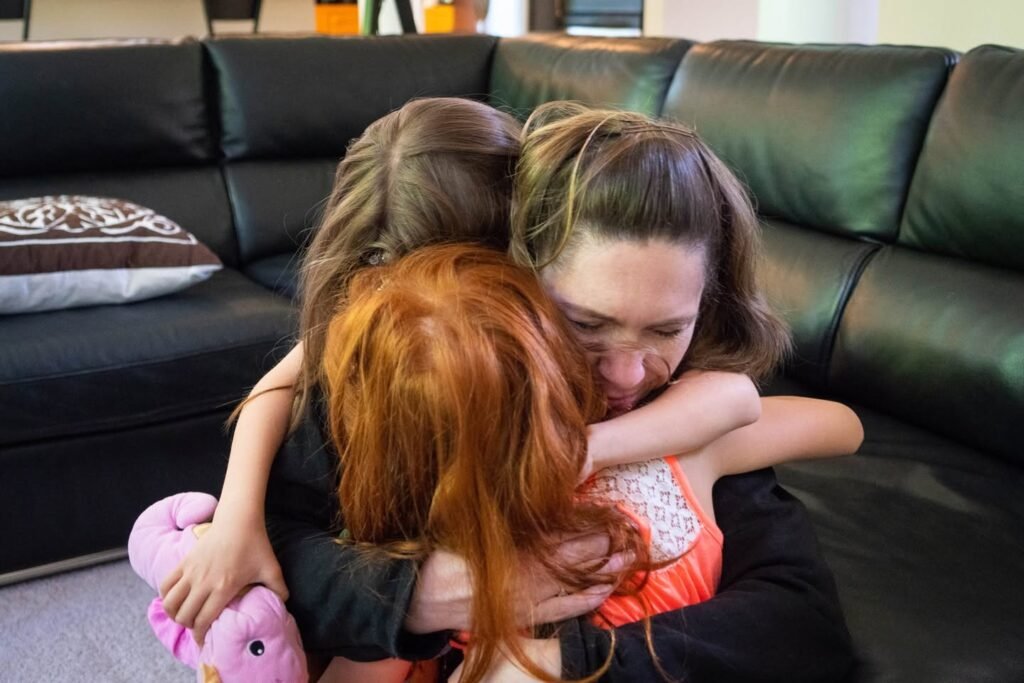 A loving family moment captured on a black leather couch.