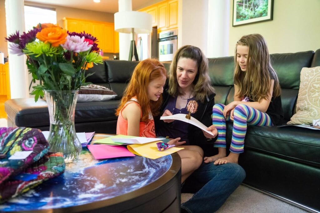 A family spends time together at home, with colorful flowers on the table. The setting is cozy and bright.