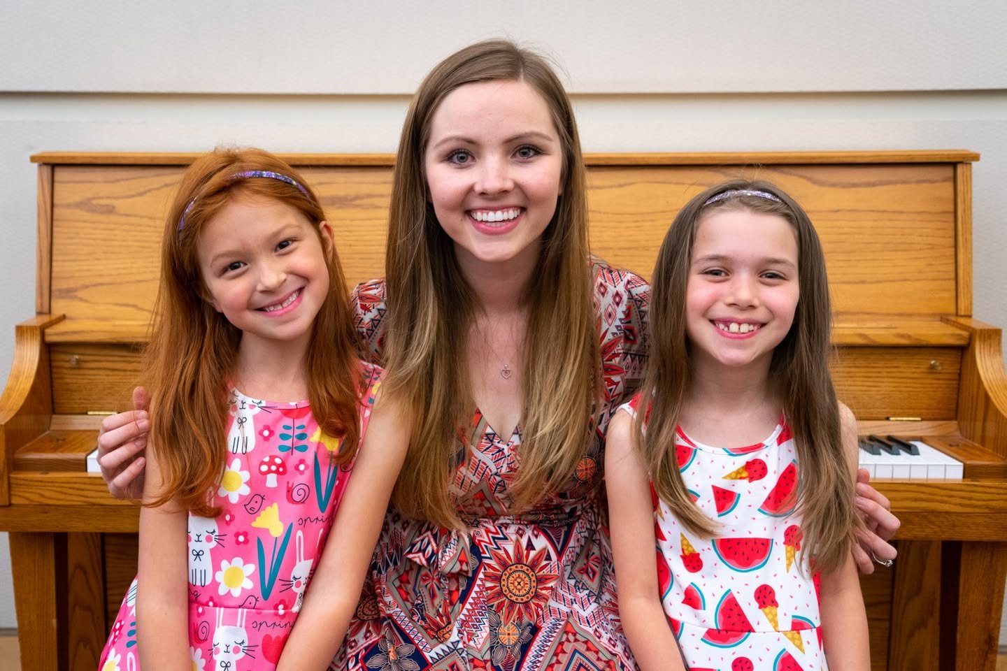 Spring 2018 Piano Recital A woman and two girls smiling together in front of a piano.