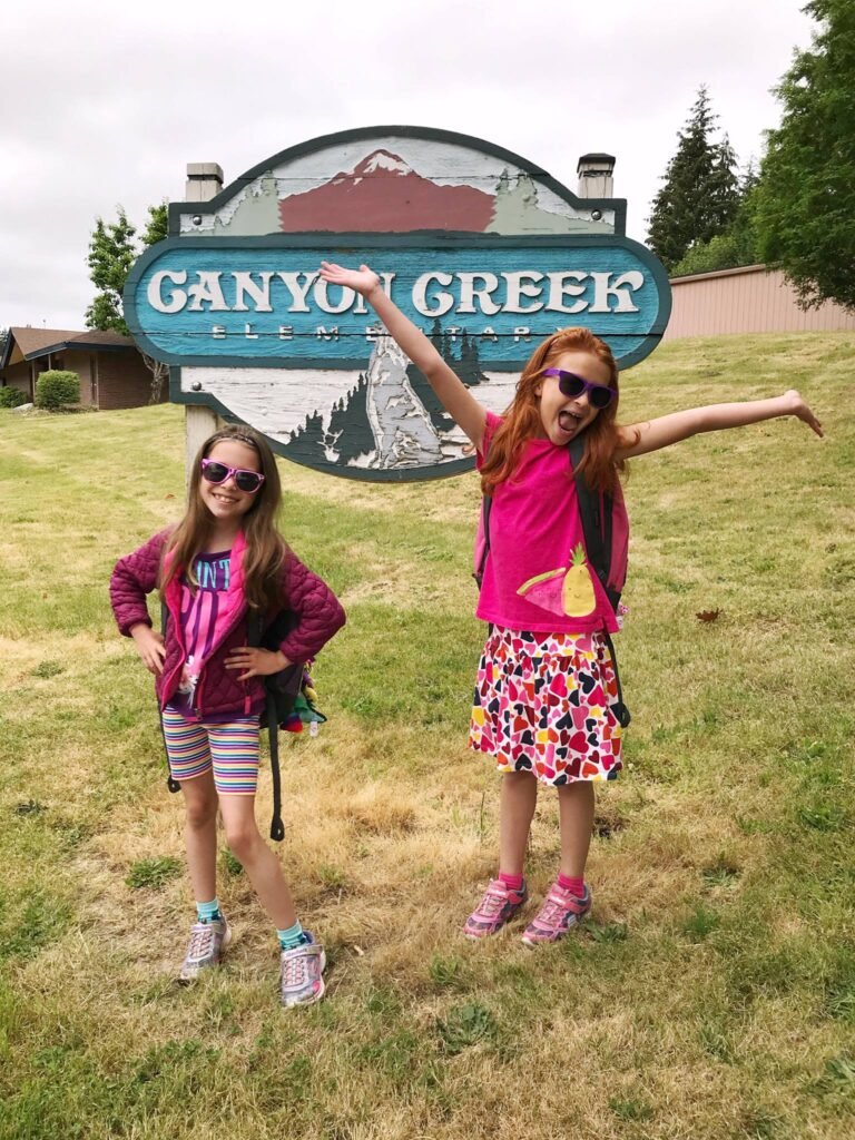 Kids posing in front of the Ganyo Creek resort sign in a grassy field.