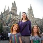 Bakersfield A family poses for a photo in front of the iconic castle at Hogsmeade. The setting captures the magical atmosphere of a theme park visit.