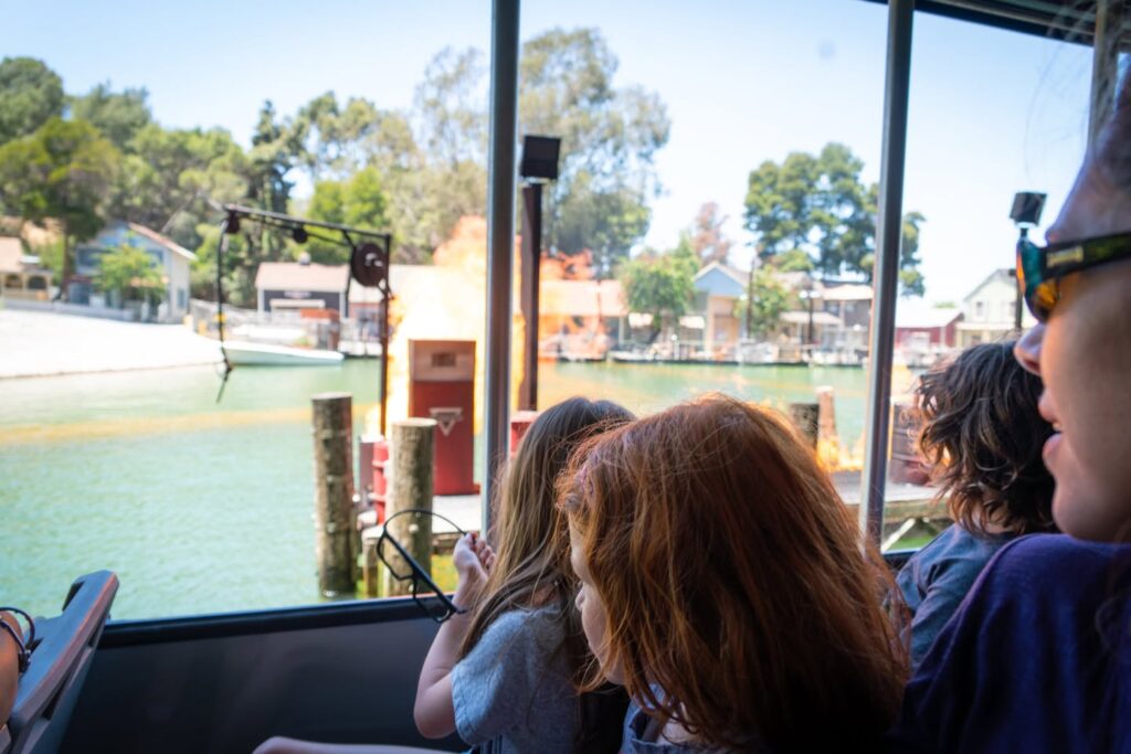 A group enjoying a boat ride past trees and docks. Panoramic view of the waterfront landscape.