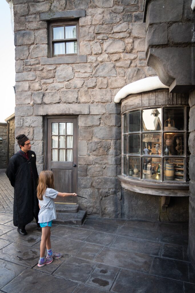 A family exploring a stone building exterior featuring a distinctive protruding bay window and textured masonry walls.