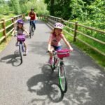 A family enjoying a scenic bike ride on a paved path surrounded by lush greenery.