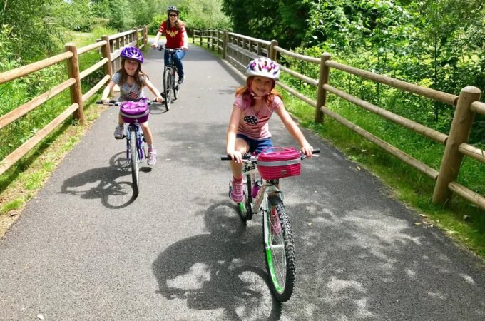 A family enjoying a scenic bike ride on a paved path surrounded by lush greenery.