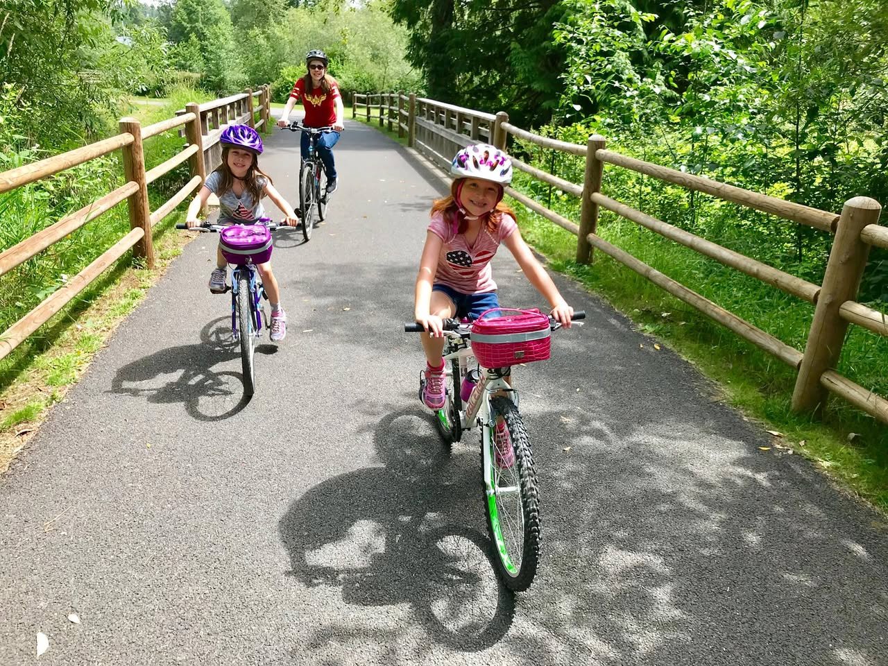 Tambark Creek Park A family enjoying a scenic bike ride on a paved path surrounded by lush greenery.