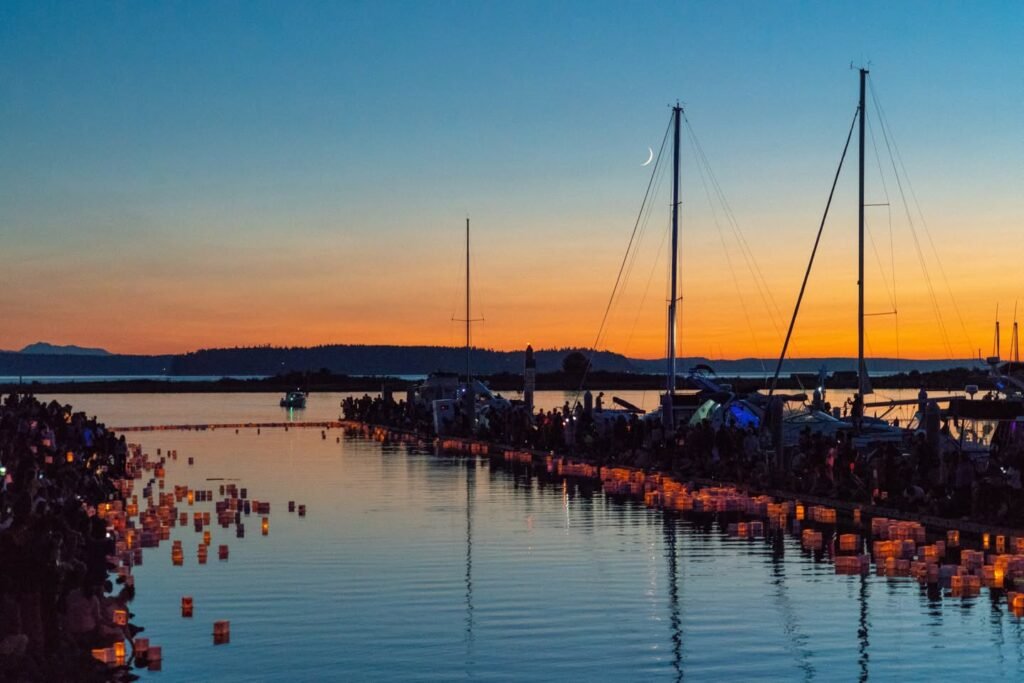A serene sunset at a coastal marina with sailboat masts reflected in calm waters.