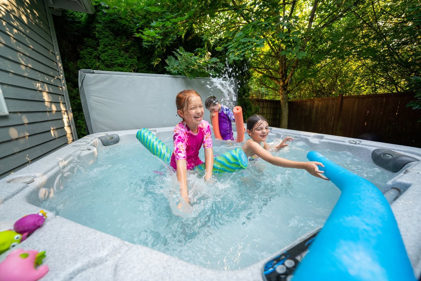91 degrees today A group of kids playing in a hot tub with a water cannon and toys on the edge.