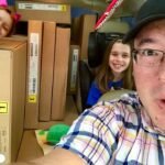 A family travels in a car packed with cardboard boxes, capturing a unique moment of fun and adventure together.