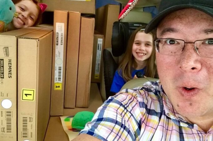 A family travels in a car packed with cardboard boxes, capturing a unique moment of fun and adventure together.