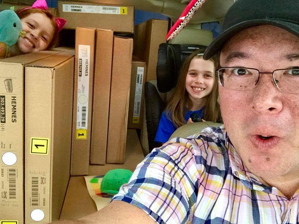 A family travels in a car packed with cardboard boxes, capturing a unique moment of fun and adventure together.