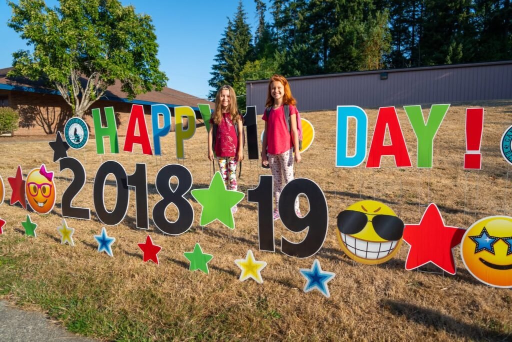 A group of people posing with colorful 'Happy Day' and '2018' signs outdoors.