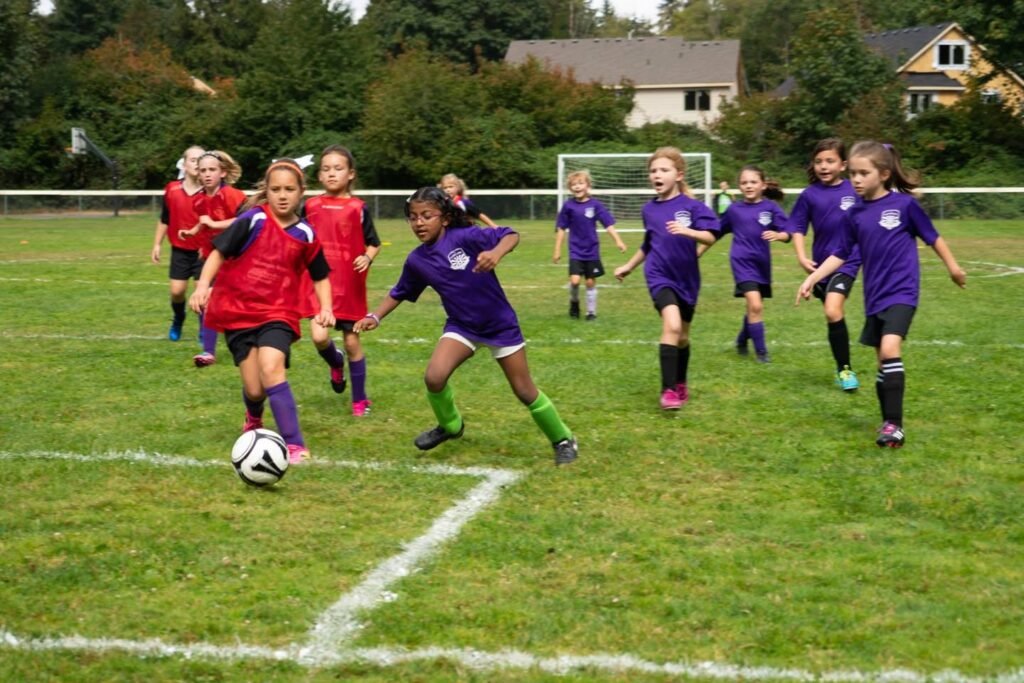 Two teams of young soccer players compete on a suburban field in a friendly match.