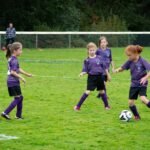 Four young players in purple uniforms compete for the ball on a green soccer field. The lower image shows close-ups of players and the action.