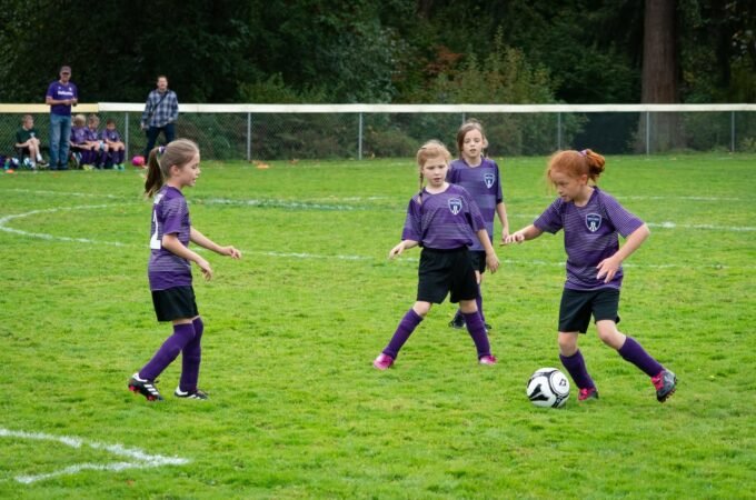 Four young players in purple uniforms compete for the ball on a green soccer field. The lower image shows close-ups of players and the action.
