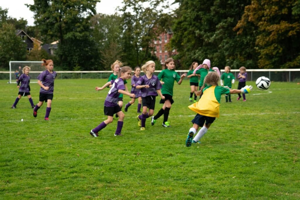 Youth soccer teams in green and purple jerseys compete on a grassy field. A close-up shows players running and a ball mid-air.