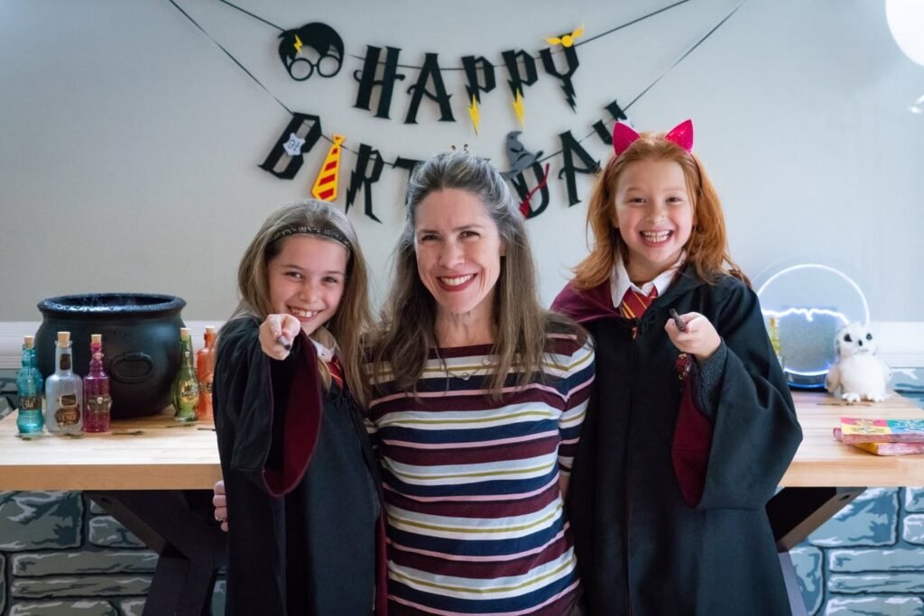A family poses for a photo at a Harry Potter themed birthday party with festive decorations and magical props.