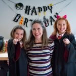 A family poses for a photo at a Harry Potter themed birthday party with festive decorations and magical props.