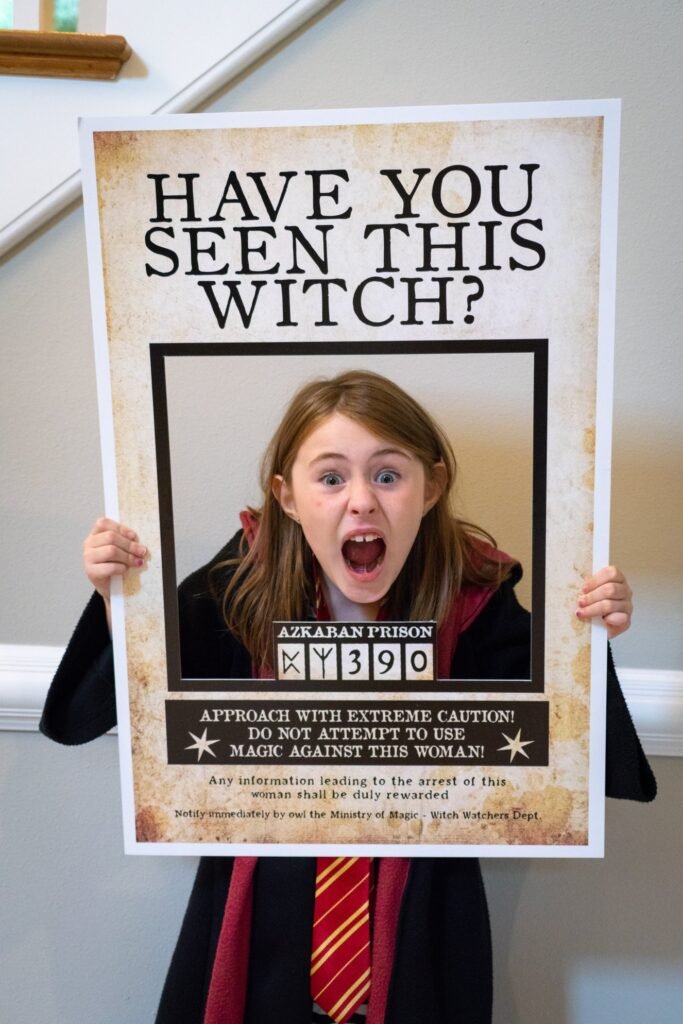A person holds a custom 'Have You Seen This Witch?' sign as a fun costume accessory, prominently featuring a mugshot-style photo.