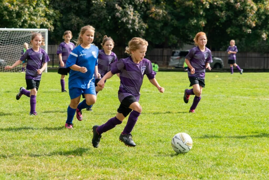 Five screenshots from a youth soccer match capturing athletic action on the grass field. The image shows players in active motion during gameplay.