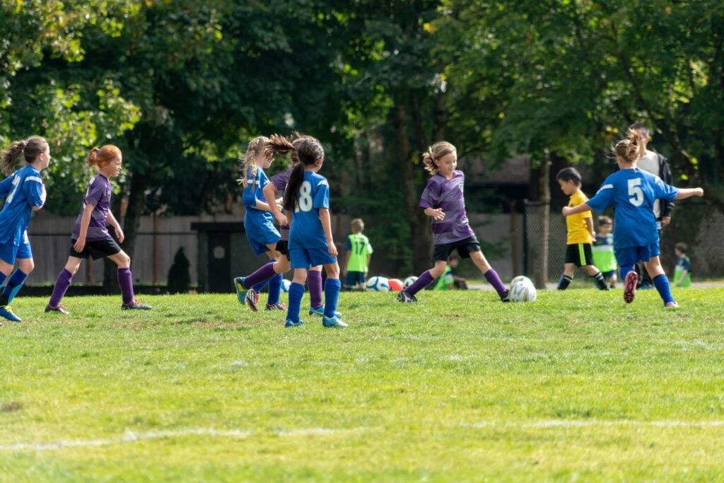 Young players compete in a soccer match on a sunny, grassy field.