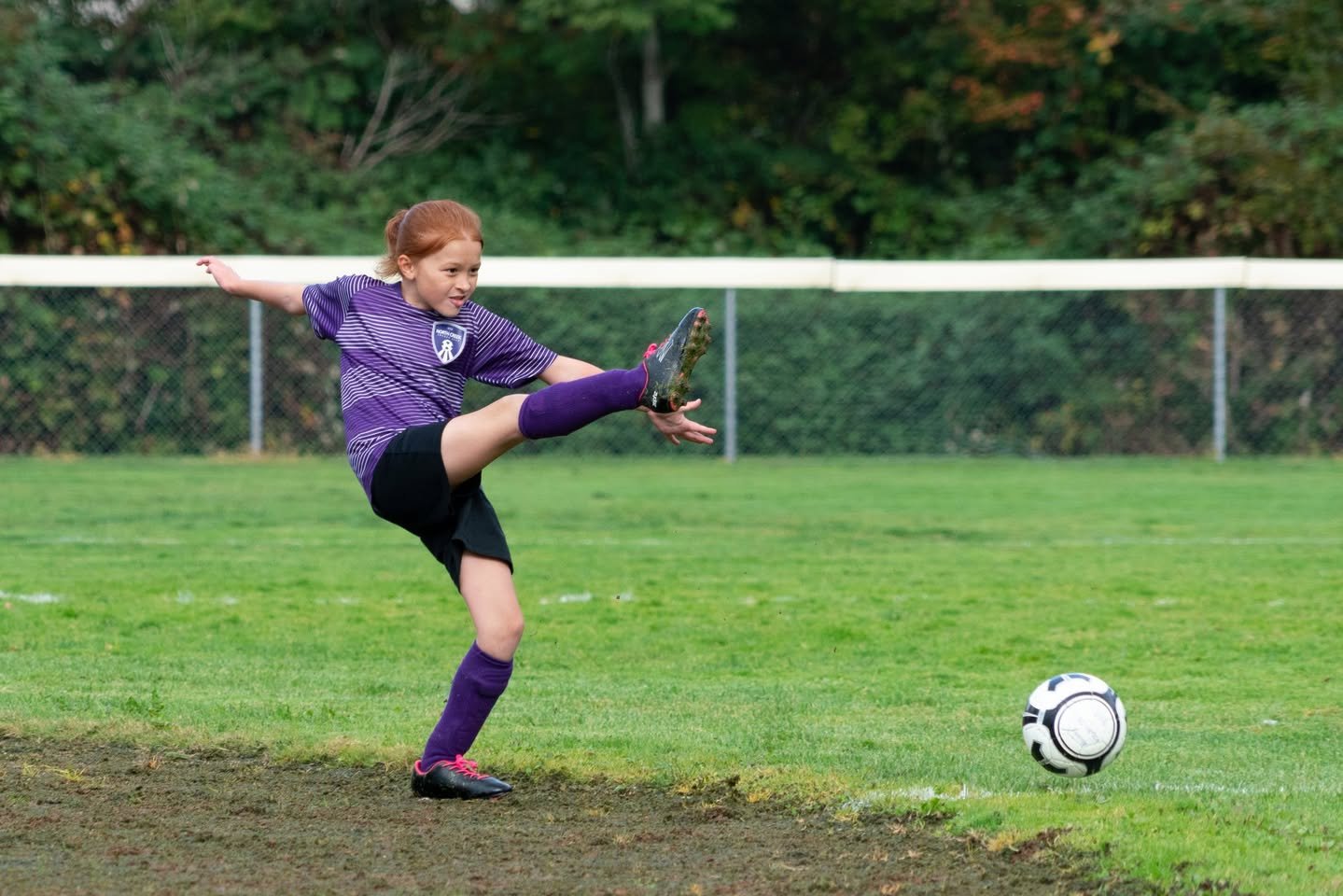 Alicorns vs Kickers A soccer player in a purple uniform kicks a ball during an outdoor game.