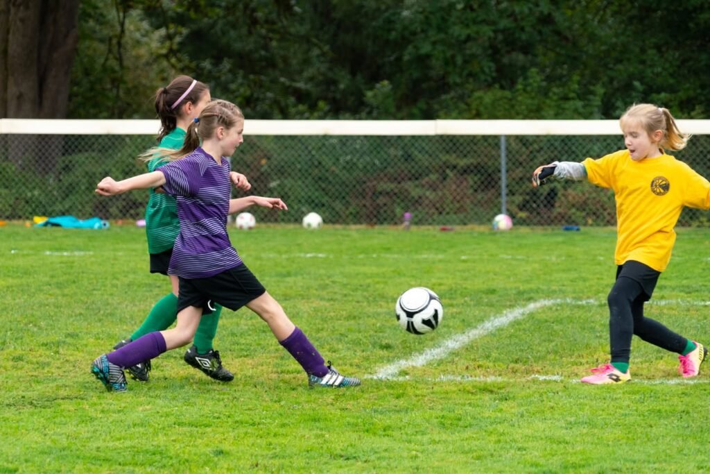 Youth soccer players competing for the ball on a grassy field.