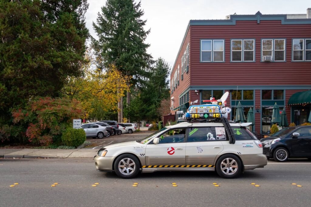 A white tour van drives past a red brick building in a downtown area.