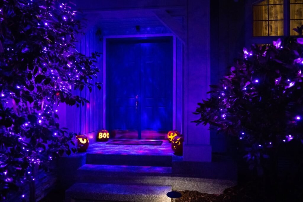 A home entrance decorated with purple lights and jack-o'’lanterns for Halloween night.
