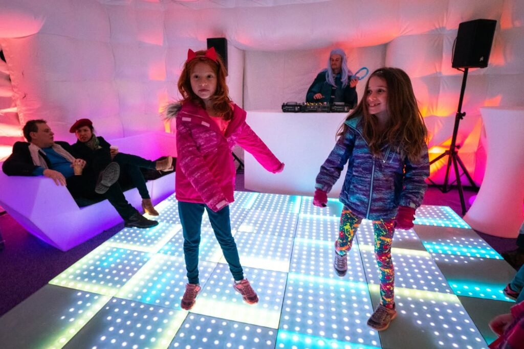 Children dancing on a colorful LED dance floor inside a bubble dome.