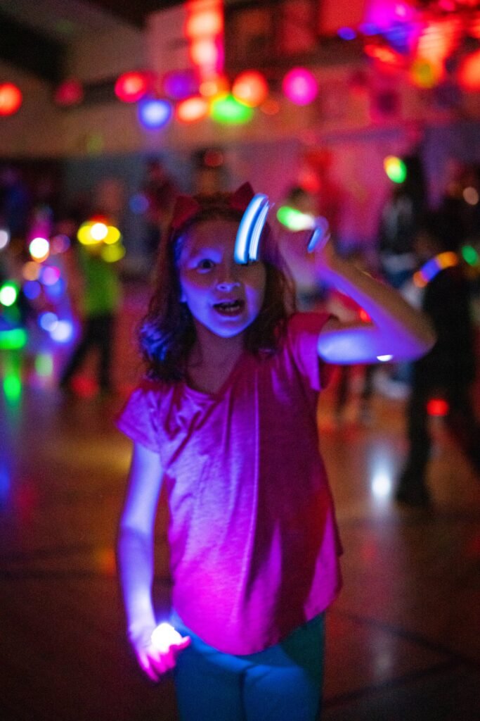 A person enjoying a glow-in-the-dark dance under vibrant purple and pink lights.