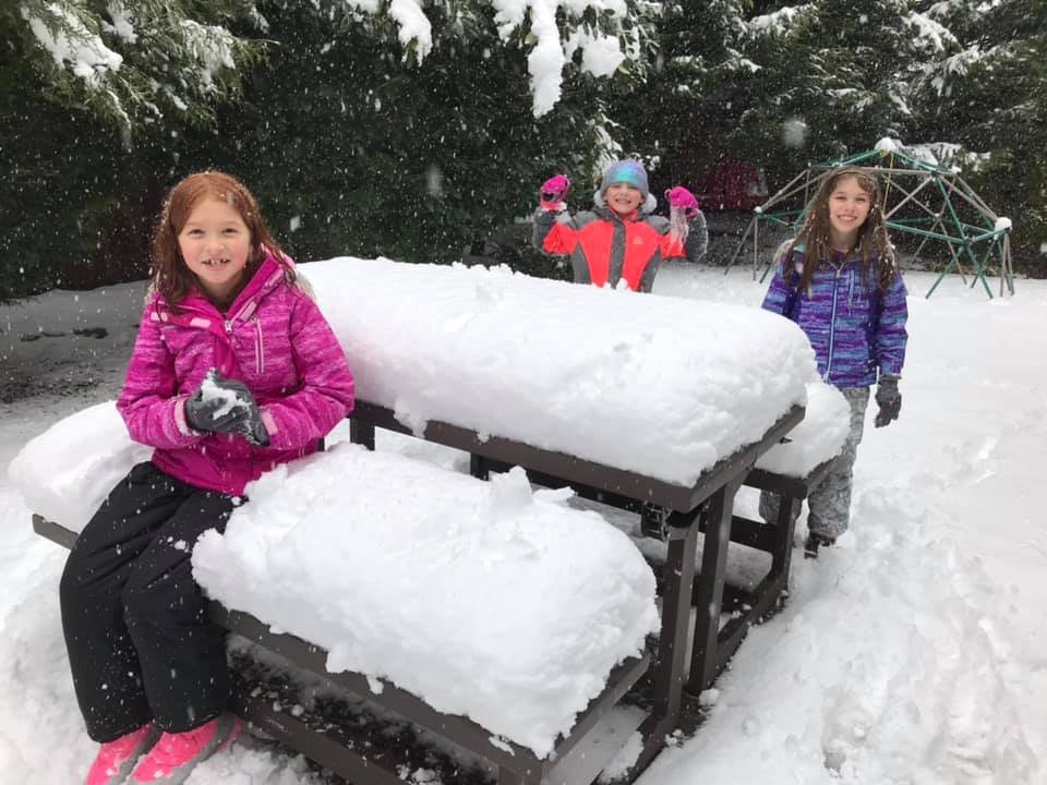 Enjoying a snowy day at the playground with snow-covered benches and trees.