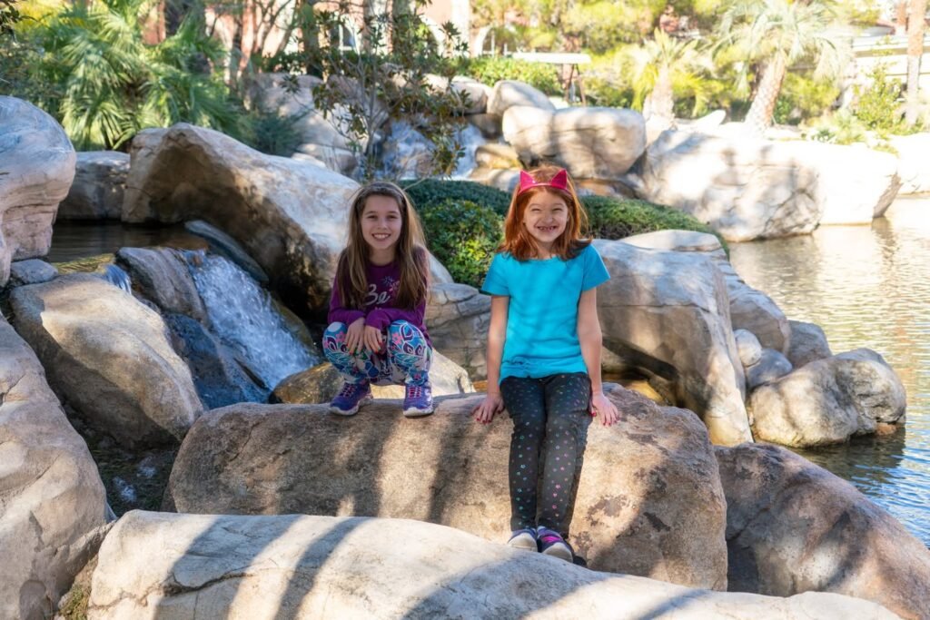 Visitors sitting and standing on large rocks near a waterfall.