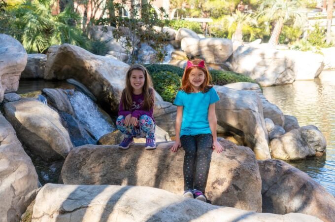 Visitors sitting and standing on large rocks near a waterfall.