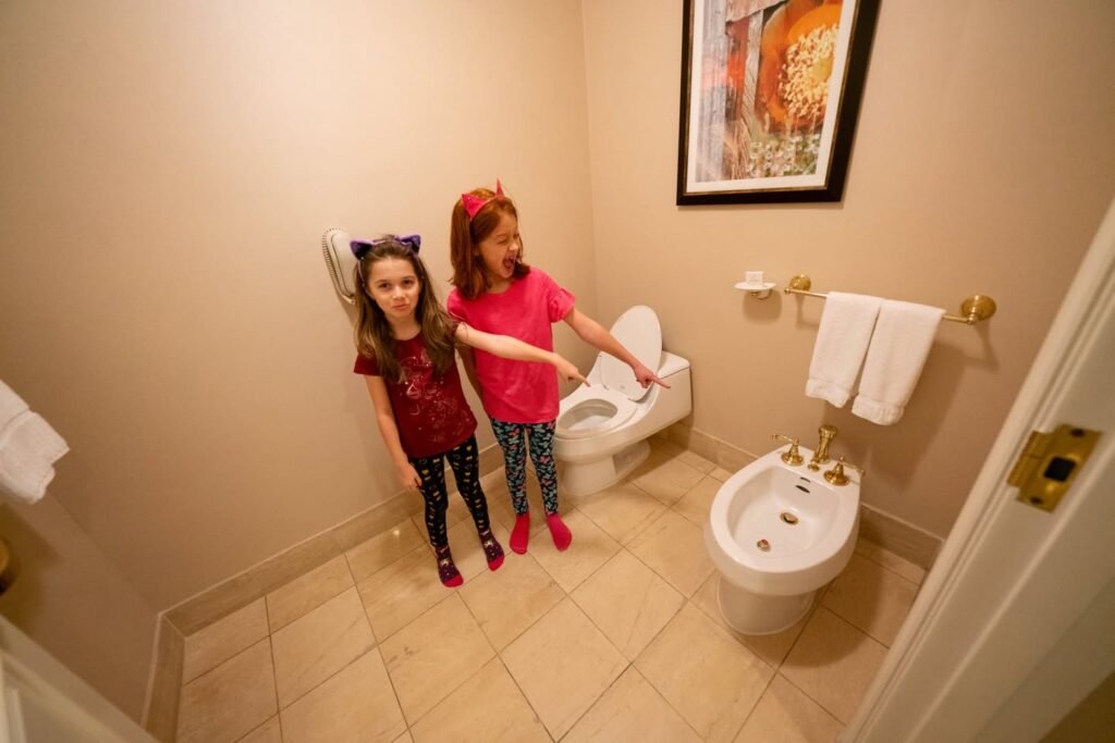 A cozy hotel bathroom featuring a white bidet and toilet, with warm lighting and beige tiles.